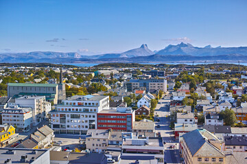 Aerial view of Bodo city in Norway on a sunny day with a blue sky. Scenic modern urban landscape of streets and buildings near a mountain horizon with copy space. Peaceful rural town from above