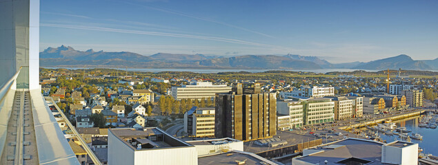 Cityscape view of urban city buildings and infrastructure with background mountains in popular overseas travel destination. Busy downtown centre and urban architecture and blue sky in Bodo, Norway