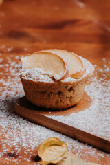 Cupcake casero con rodajas de manzana, rodeado de azúcar encima de mesa de madera, deliciosos dulces de pastelería, desayuno rústico de manzana