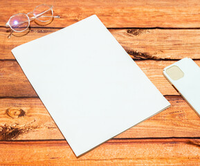 Mockup of a white blank magazine cover on the top of a wood textured background