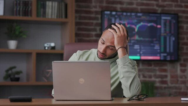 Unhappy businessman trader surprised by the bad news on laptop. Disappointed african american broker worries about bankruptcy, debt, get no profit. The fall of stock market and cryptocurrencies.