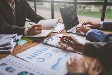 A business team consultant describes a marketing plan to set business strategies for business owners using a calculator. business planning and business researching concept.