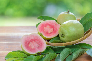 Sweet Red Guava fruit with leaf on blur garden background, Fresh Pink Guava fruit on wooden basket over natural farm background.