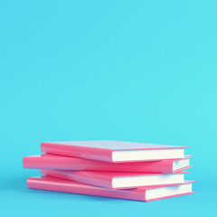 Pink stack of books on bright blue background in pastel colors
