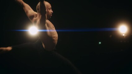 A ballet male dancer is performing choreography on classic theater stage. Choreographer is practicing dance moves. Acrobatic elements of contemporary dance. Performance concept. Slow motion.