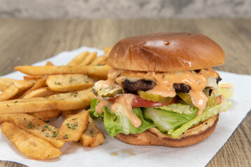 Burger with lettuce, tomato, pickle, and secret sauce with pepper steak fries for a party appetite hunger meal