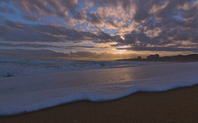puesta de sol contra el sol en la playa con nubes en el horizonte