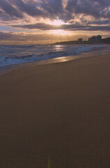 puesta de sol contra el sol en la playa con nubes en el horizonte