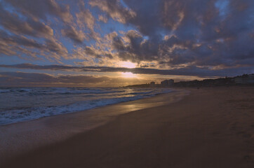 Fototapeta na wymiar puesta de sol contra el sol en la playa con nubes en el horizonte