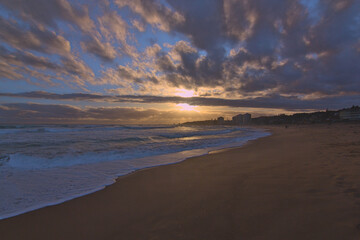 Fototapeta na wymiar puesta de sol contra el sol en la playa con nubes en el horizonte