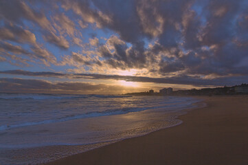 puesta de sol contra el sol en la playa con nubes en el horizonte