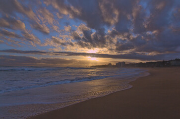 puesta de sol contra el sol en la playa con nubes en el horizonte