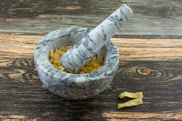 Crushed wonton strips in mortar and pestle on table to make crunchy ingredient for cooking - obrazy, fototapety, plakaty