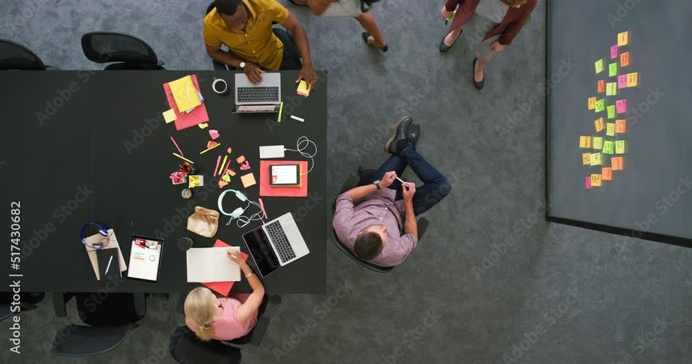 Aufkleber Group of diverse students using technology sitting in a corporate workplace from above. Bright informal office space to improve creativity. Creative spot for staff to relax and browse the internet