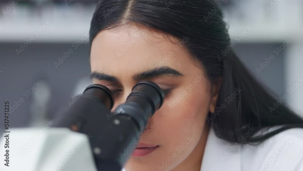 Poster closeup of a young female scientist using a microscope analysing medical test results or samples in 