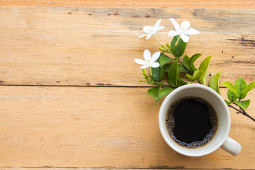 Obraz na płótnie Canvas hot coffee with white flowers jasmine arrangement flat lay postcard style on background wooden