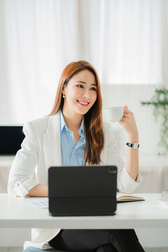 Freelance Asian woman working on a computer tablet in a modern office. make an account analysis report on real estate investment information financial system concept and tax vertical picture