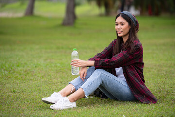 Beautiful Asian woman drinking clean water from plastic bottles.