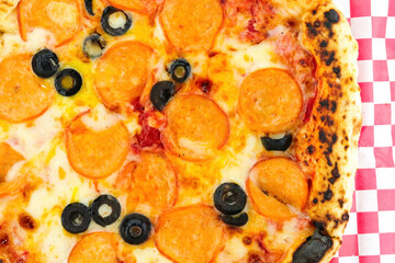 Chicken pepperoni pizza with black olives on red checkered paper