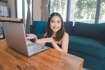 A young Asian woman is smiling while sitting on the couch in the living room.
