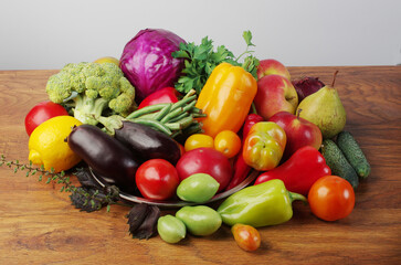Fresh vegetables eggplant, tomatoes, cucumbers, peppers, green beans on a wooden table.