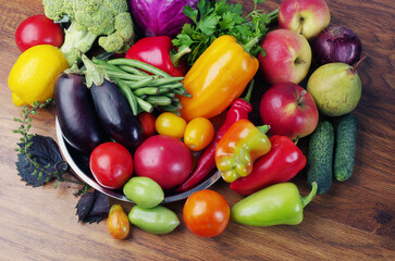 Fresh vegetables eggplant, tomatoes, cucumbers, peppers, green beans on a wooden table.