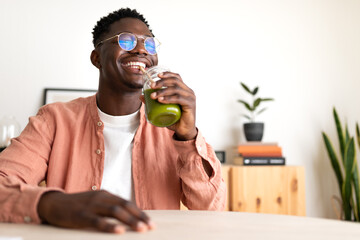 African American black man drinking healthy green juice with bamboo straw looking at camera. Copy...