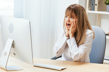 Shocked upset adorable blonde businesswoman worker touch chin both hands thinking of problem solution in light modern office. Employee work on computer online pondering or making decision. Copy space