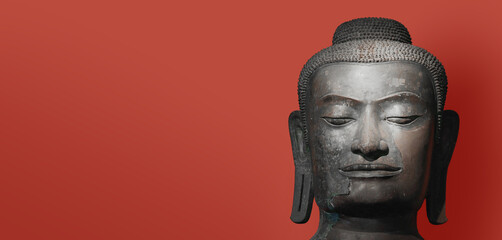 The head of an ancient Buddha statue was made of bronze. image on copy space classic red background.