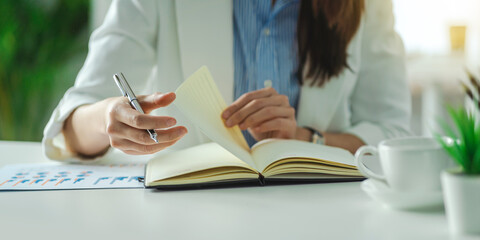 Young Asian woman sitting at a table and writing notes. Businesswoman working at her desk.