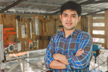 Young asian small business owner in the woodwork workshop and calling on phone with customer.