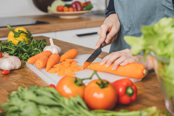 Asian housewife woman slice carrot to preparing salad ingredients for dinner meal  in the kitchen