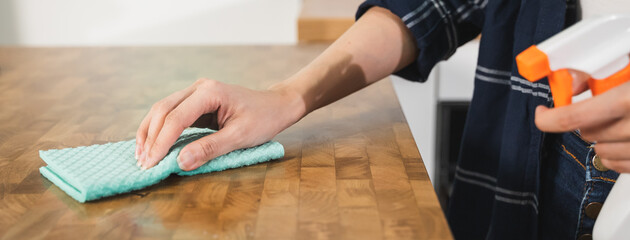 housewife cleaning wooden table by cloth and cleaning solution