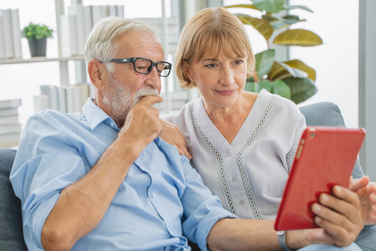 relaxed mature couple using laptop computer shopping online in the living room.