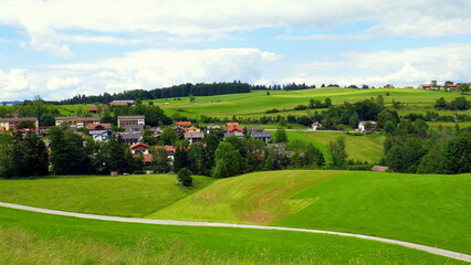Fototapeta na wymiar Panorama von Bad Kohlgrub im Ammergau mit Häusern, Wald, Weg und grünen Wiesen am Morgen