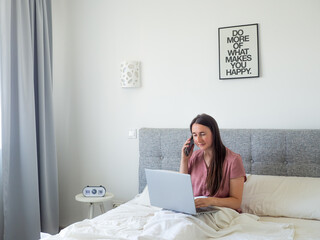 Woman working with laptop on the bed. Digital nomad and work from home concept. Young business...