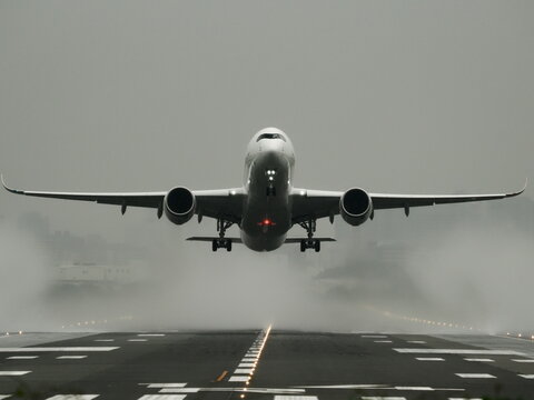雨の日に水煙を上げて離陸する旅客機
