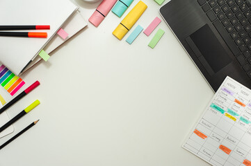 Colorful stationery, a school schedule and a cup of cocoa are laid out on a white table. Flat lay. Copy space