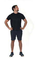 Fototapeta premium front view of man wearing sportswear shorts, looking away and arms akimbo isolated on white background