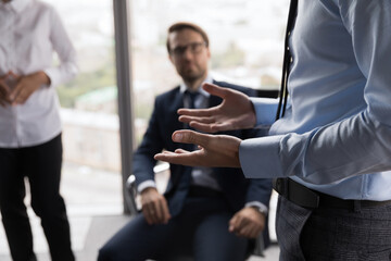 Hand gesture of male business leader talking to employees at meeting in office. Mentor, teacher...