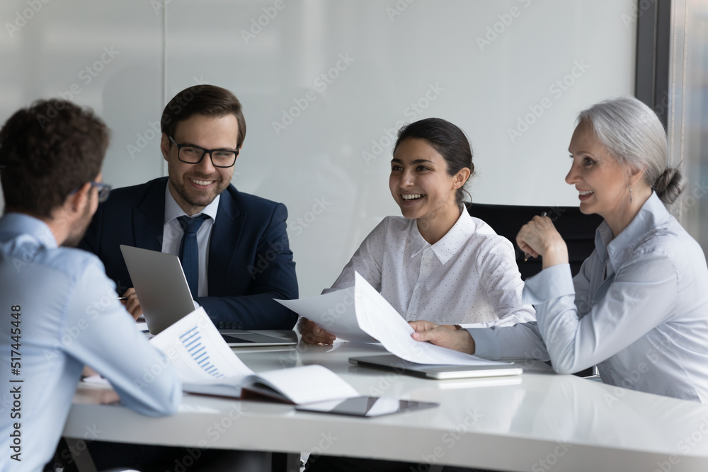 Wall mural happy different aged diverse business group negotiating on marketing reports, talking, discussing st