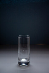 an empty tall glass stands on a blue background