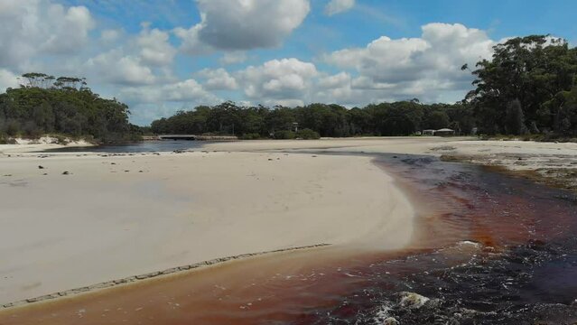 Drone video of Moona Moona Creek and Huskisson beach area after recent flooding with brown dirty water flowing into the bay