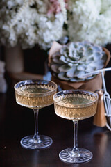 A bouquet of white hydrangeas and pink astilba, succulent, candles and a fashionable glass for dessert and champagne with wine inside. Cozy interior. The concept of a party, wedding and holiday.