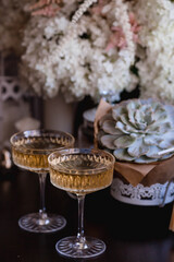 A bouquet of white hydrangeas and pink astilba, succulent, candles and a fashionable glass for dessert and champagne with wine inside. Cozy interior. The concept of a party, wedding and holiday.