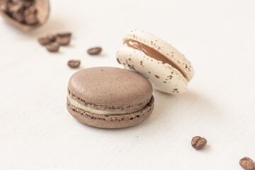 Traditional French dessert for coffee. White and chocolate creamy macarons, coffee beans on white background. Freshness concept.