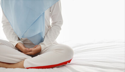 Close up young asian woman hand sitting on bed and enjoying meditation. Beautiful girl in muslim...