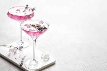Stunning Lavender cocktail Purple drink in a glass on white background with ice and lavender flowers. .Iced cold summer drink, lemonade.