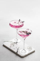 Purple Lavender cocktail drink in a glass on white board and white background with ice and lavender flowers. .Iced cold summer drink, lemonade.