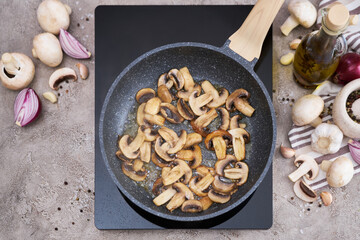 Sliced mushrooms in a frying pan on induction hob at domestic kitchen